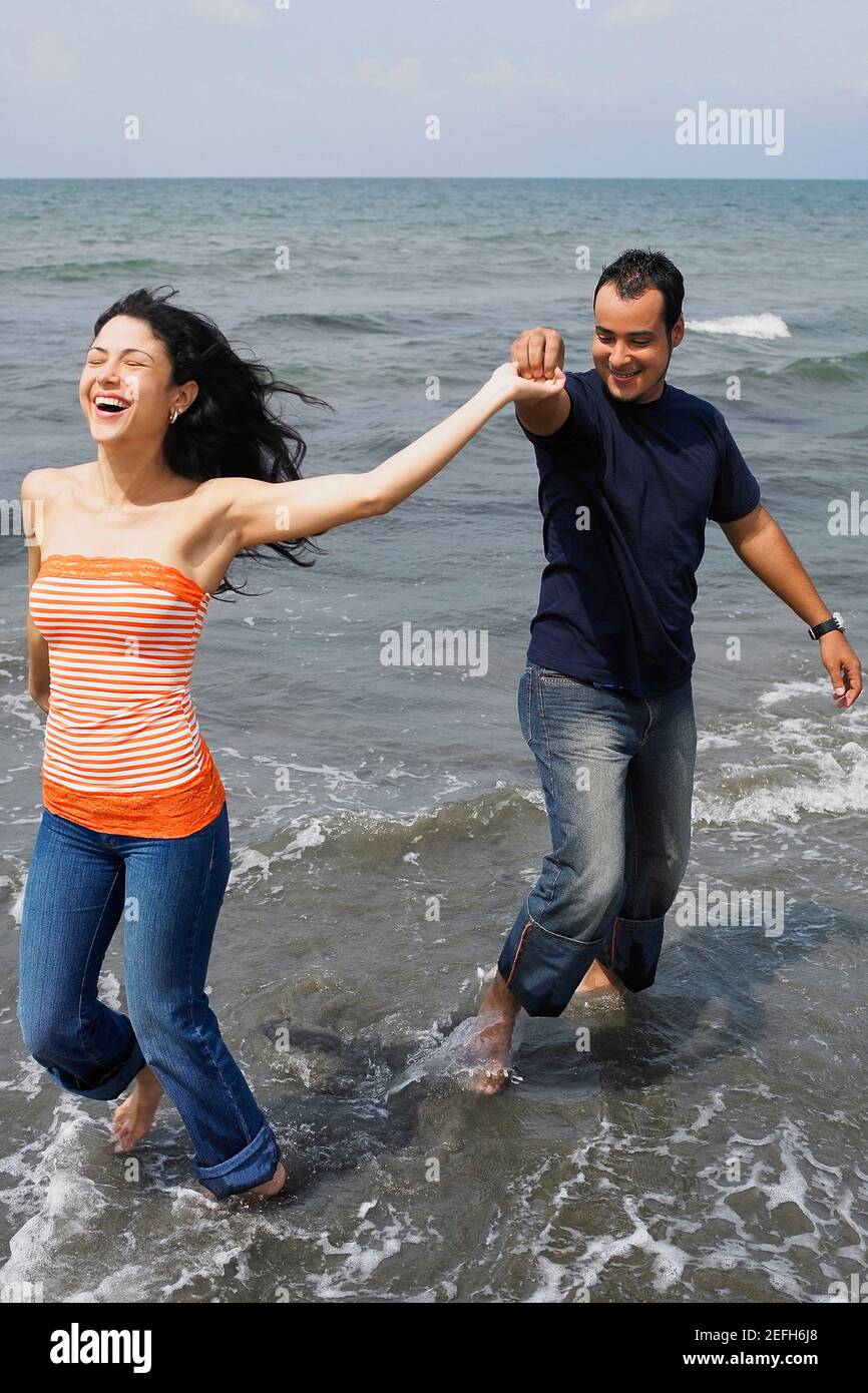Jeune couple debout sur la plage et souriant Banque D'Images