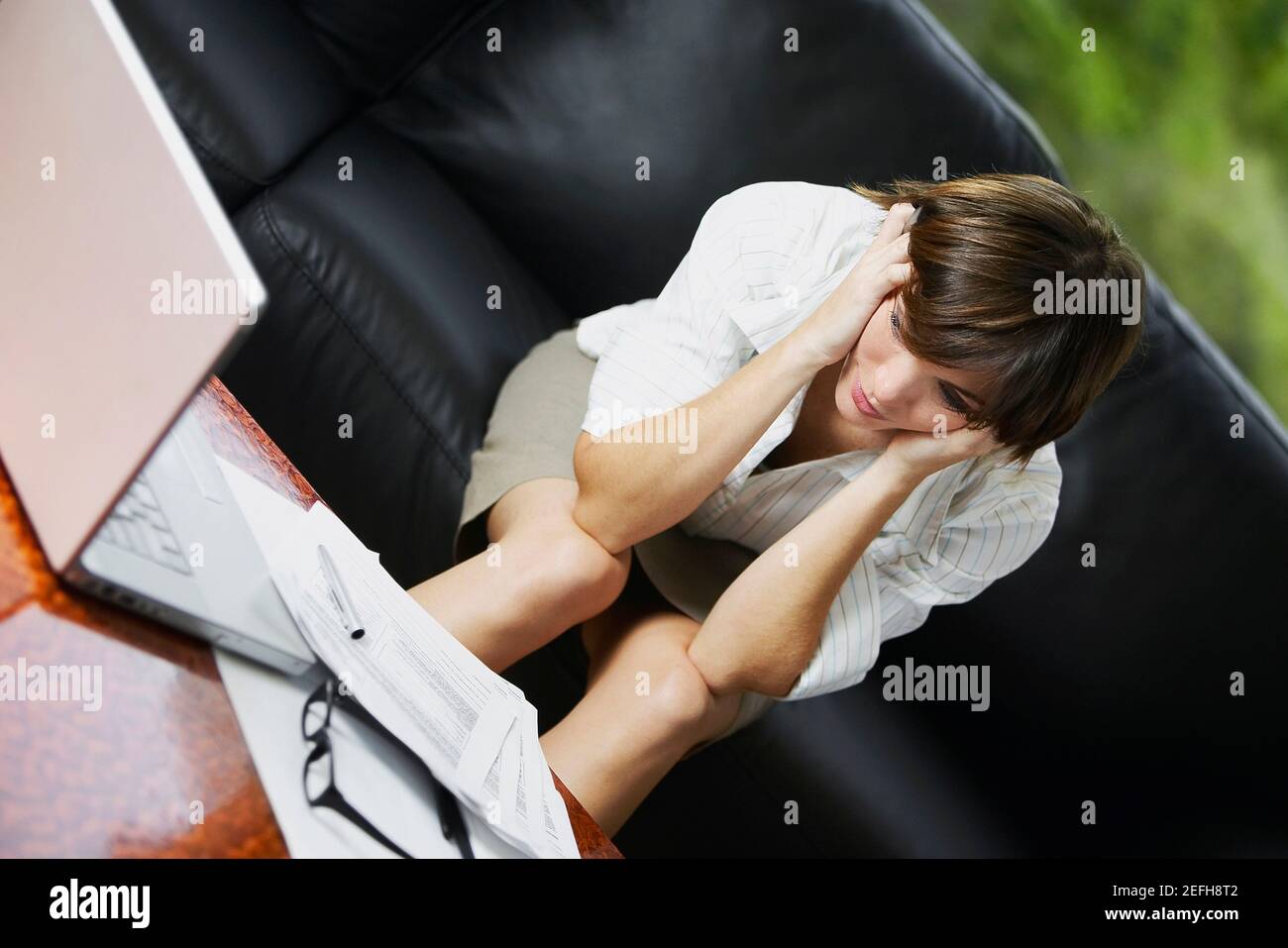 Femme d'affaires assise sur un canapé et ayant l'air inquiète Banque D'Images