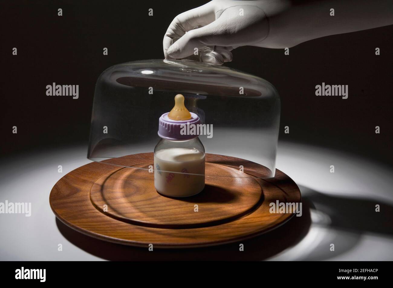 Gros plan d'une main personŽs retrait d'un récipient en verre au-dessus d'un biberon Banque D'Images