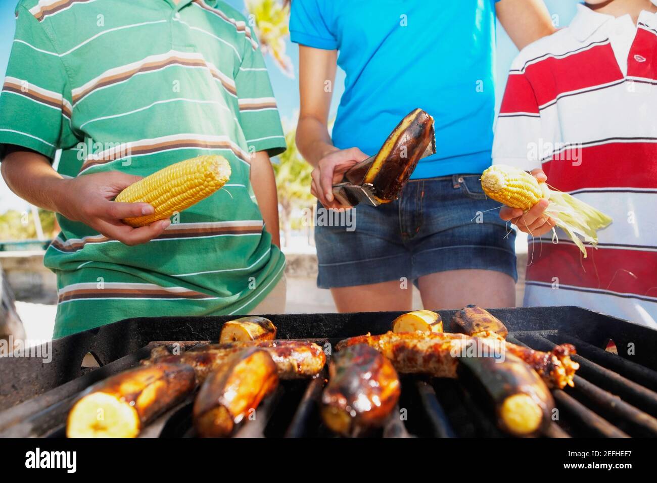 Vue en coupe centrale d'une femme avec deux enfants debout devant un barbecue Banque D'Images