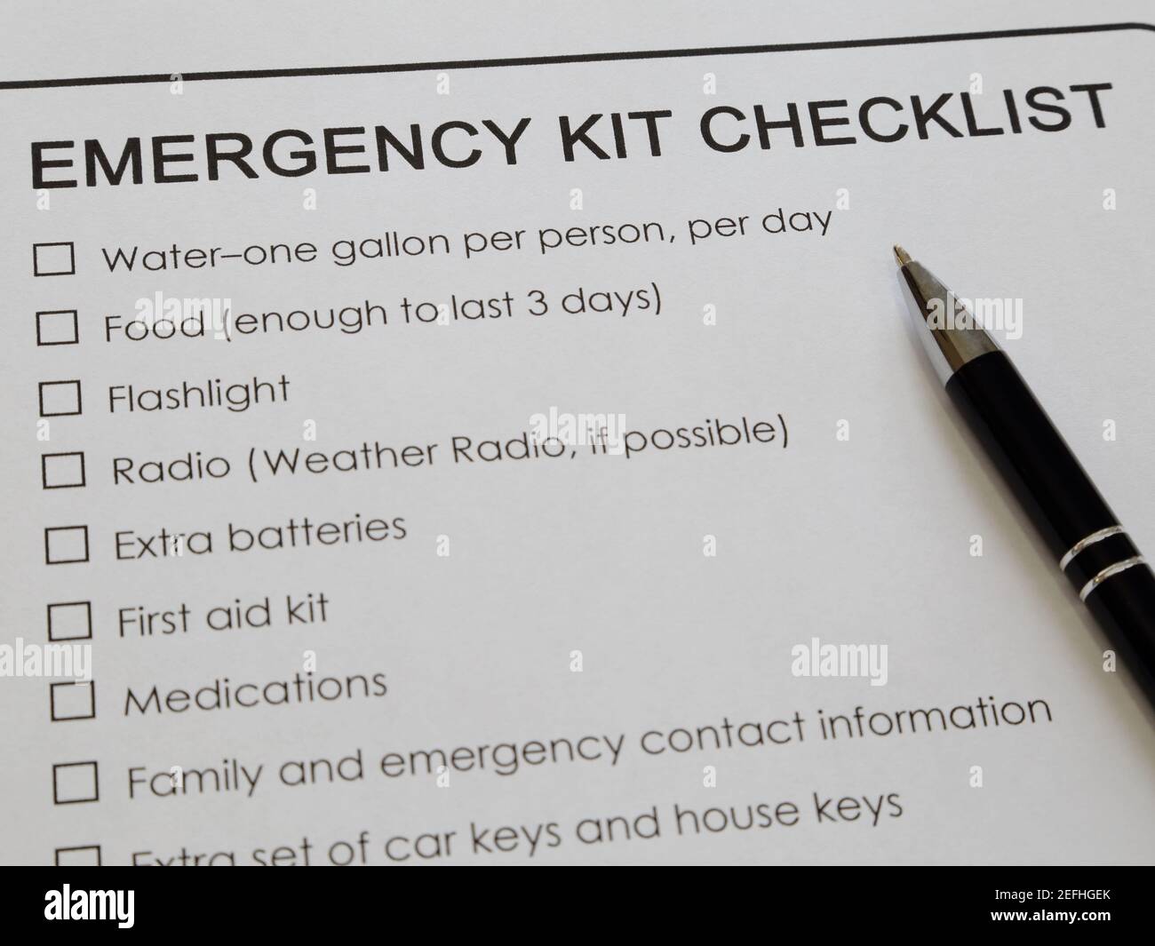 Une liste de vérification de kit d'urgence imprimée sur du papier blanc et un stylo à encre est affichée à proximité. Banque D'Images