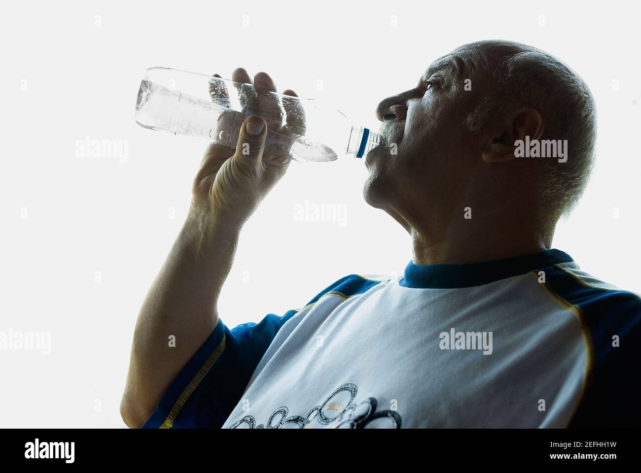 Profil latéral d'un homme mature qui boit de l'eau d'un bouteille Banque D'Images