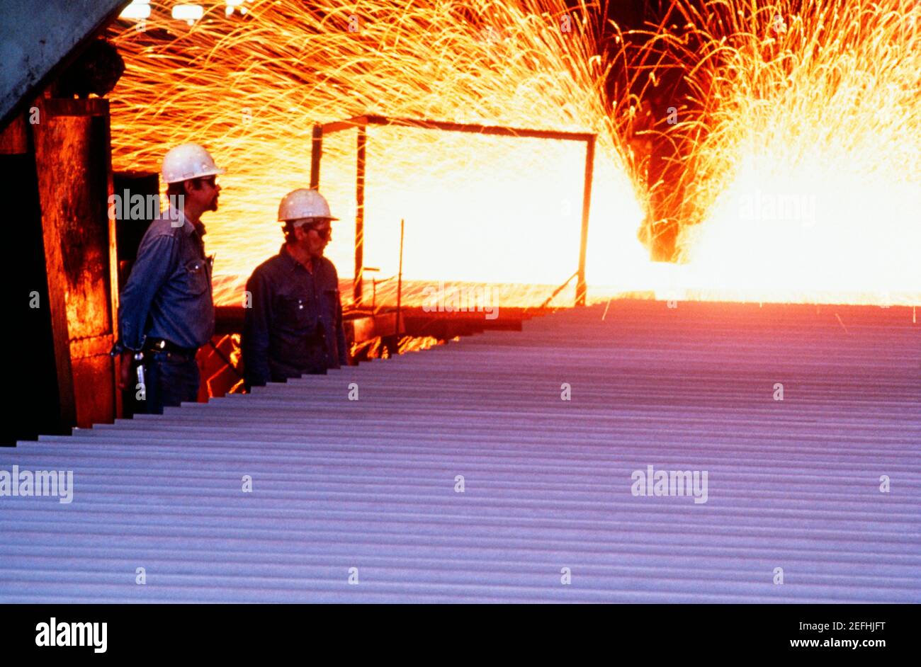 Profil latéral de deux ouvriers de fonderie debout dans un acier usine Banque D'Images