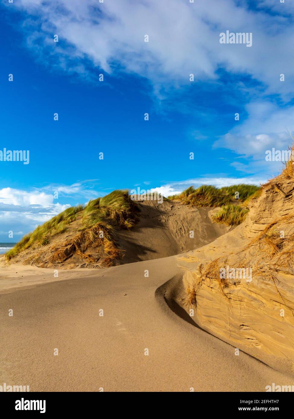 Dunes de sable sur la plage de Morfa Dyffryn entre Barmouth et Harlech à Gwynedd sur la côte nord-ouest du pays de Galles avec ciel bleu et nuages au-dessus. Banque D'Images