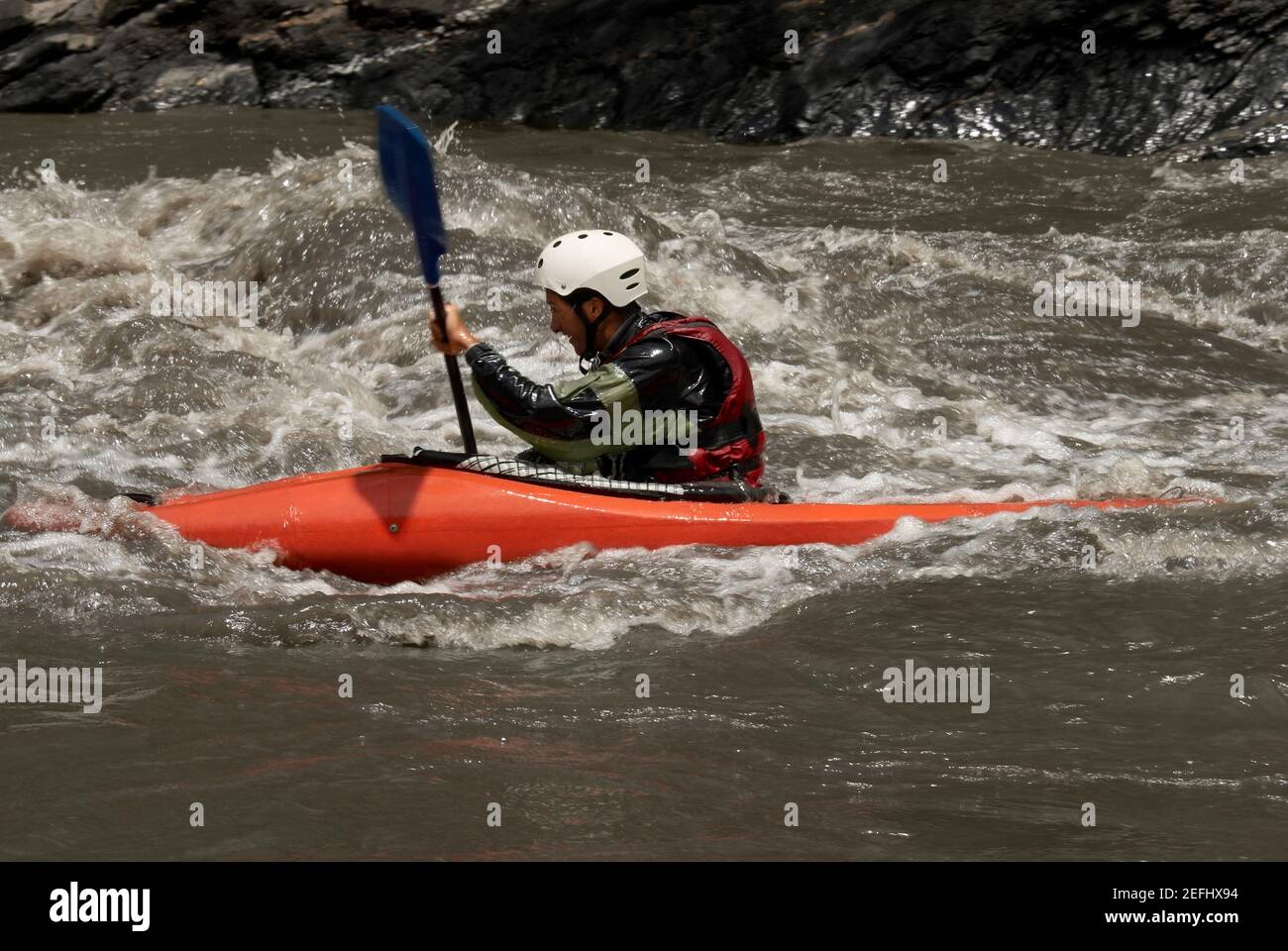 Profil d'un jeune homme en kayak dans une rivière Banque D'Images