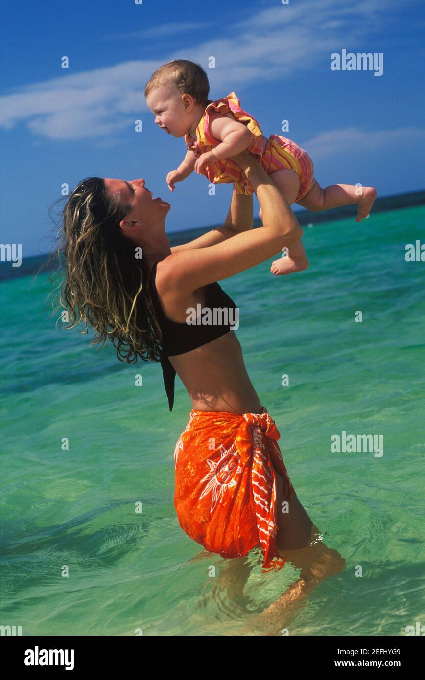 Profil d'une jeune femme portant une petite fille dans l'eau Banque D'Images
