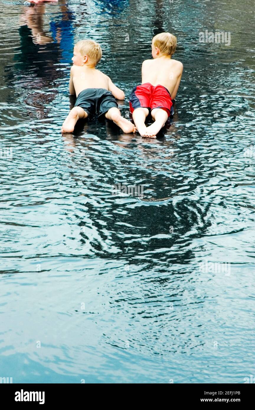 Vue arrière de deux garçons couchés dans l'eau Banque D'Images