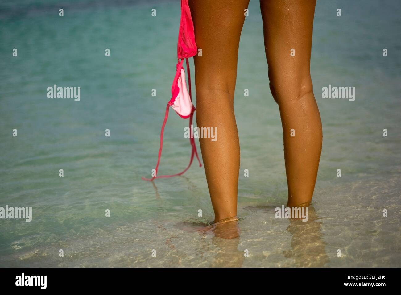 Vue en coupe basse d'une jeune femme tenant un bikini haut Banque D'Images