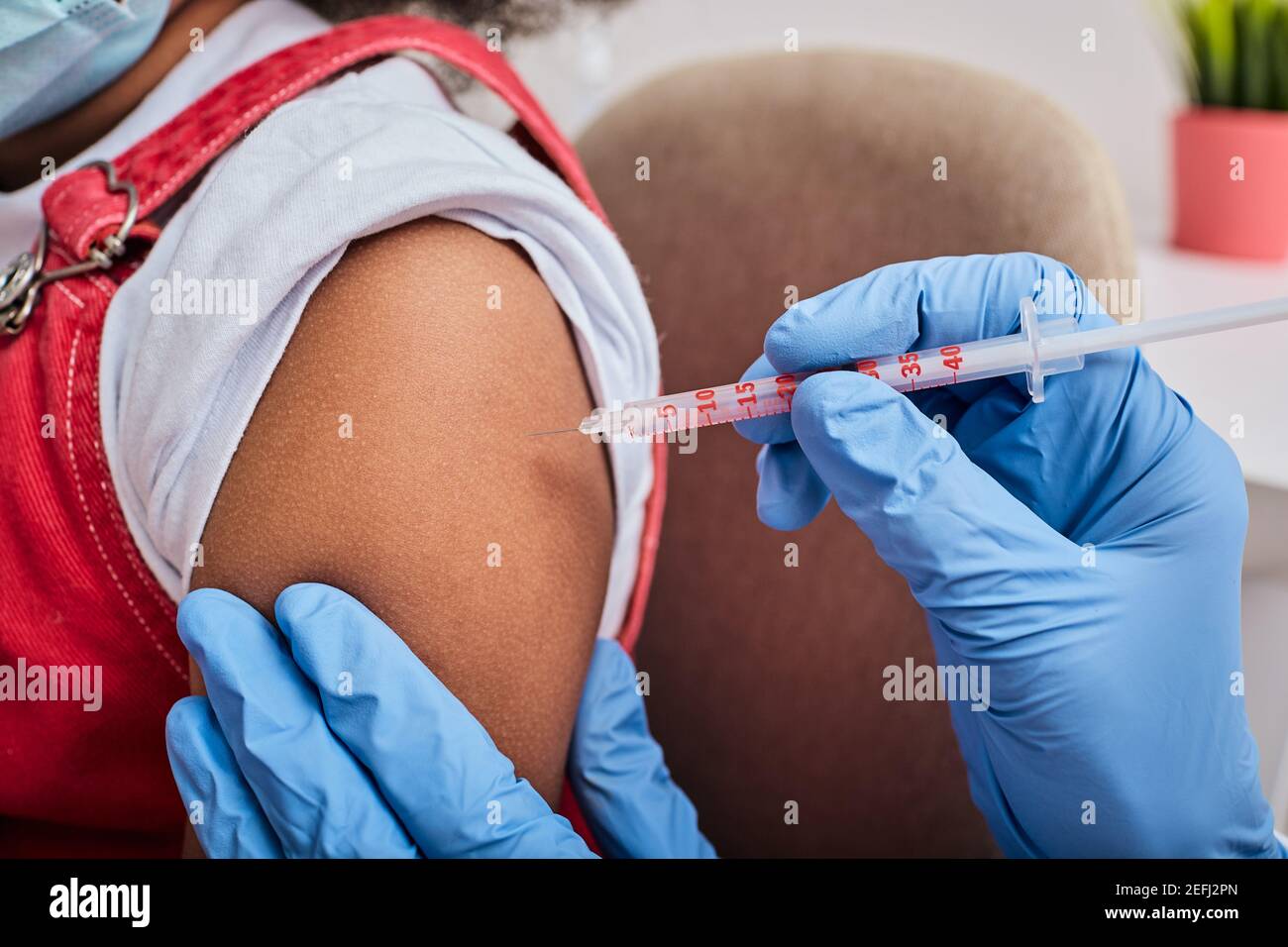 Gros plan de l'épaule de l'enfant pendant l'injection du vaccin dans un hôpital Banque D'Images