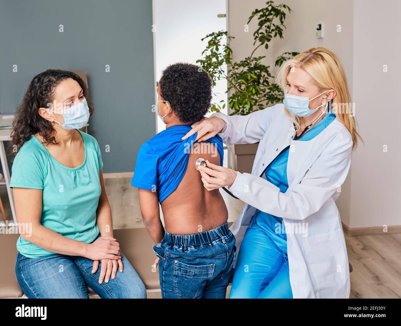 docteur auscultant le dos et les poumons du garçon à l'aide d'un stéthoscope. Un enfant afro-américain a une pneumonie ou un coronavirus Banque D'Images