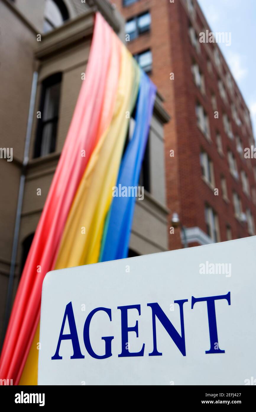 Panneau devant un drapeau arc-en-ciel suspendu à un bâtiment Banque D'Images