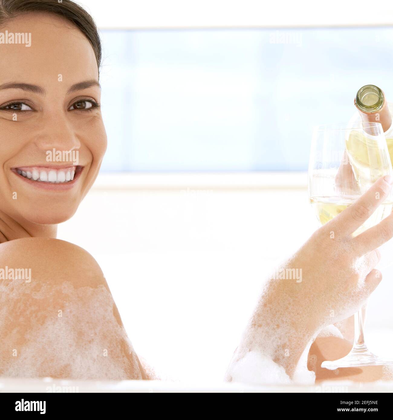 Portrait d'une jeune femme versant du vin blanc dans un wineglass Banque D'Images