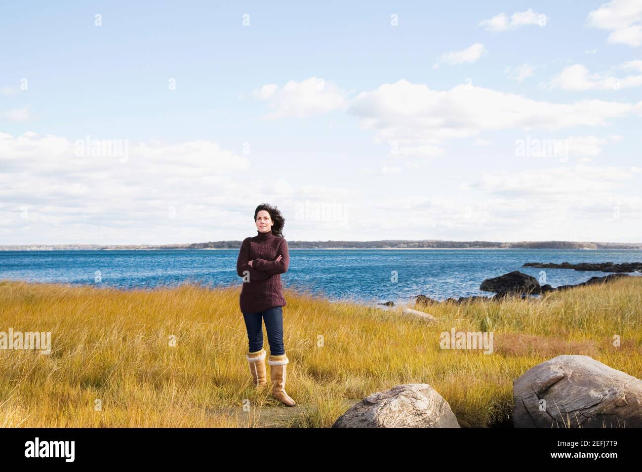 Femme mûre debout sur la plage avec ses bras croisés Banque D'Images
