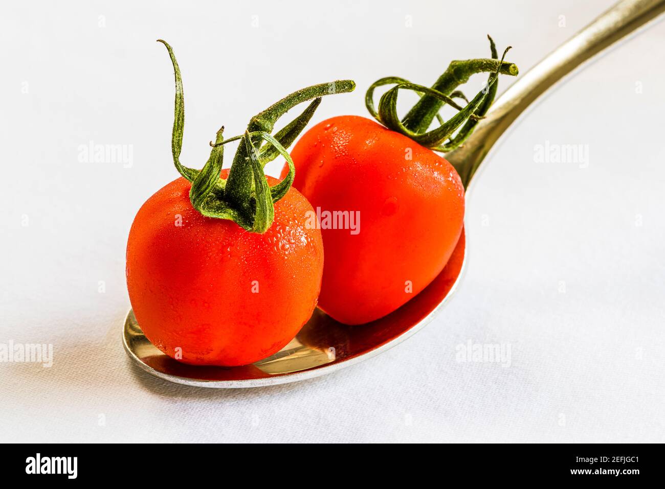 Gros plan de deux tomates rouges sur une cuillère sur une nappe blanche, Londres, Royaume-Uni Banque D'Images