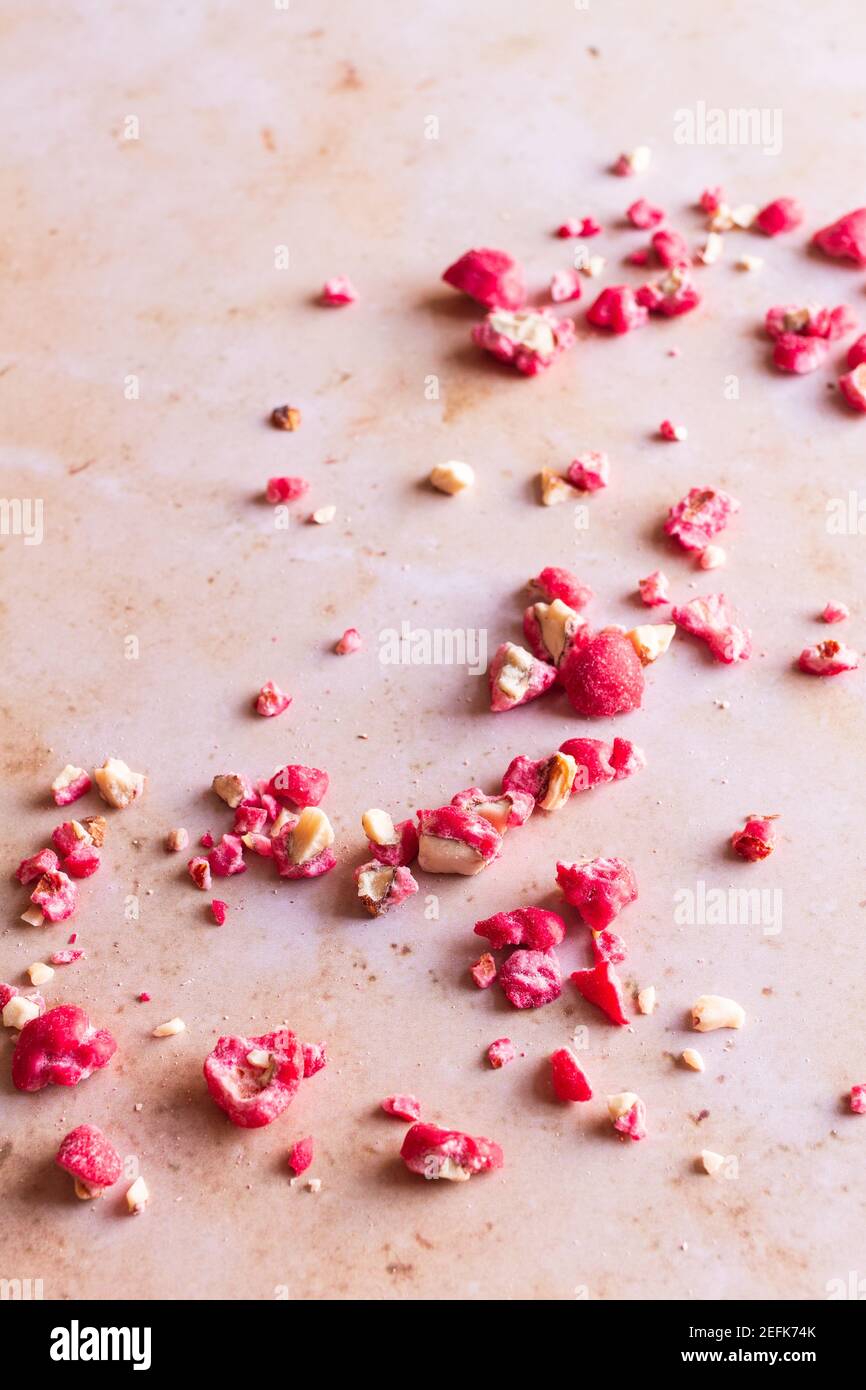 Pralines d'amande rose hachées sur fond de marbre rose. Banque D'Images