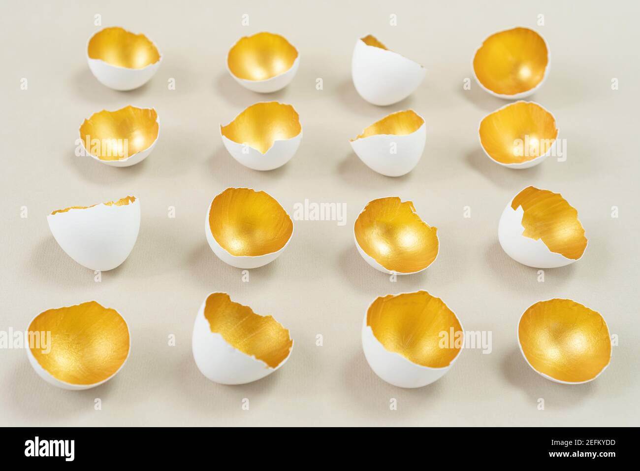 La coquille d'œuf, peinte de l'intérieur en or, se trouve en rangées paires sur un fond beige. Combinaison harmonieuse de couleurs or, blanc et ecru. Conce Banque D'Images