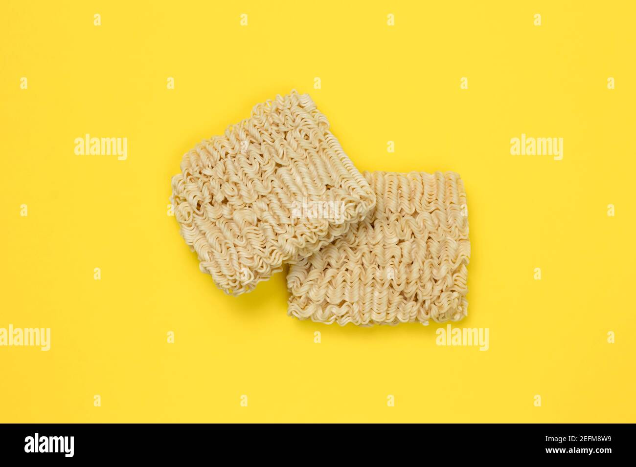 Nouilles instantanées, ramen, blocs de nouilles séchées sur fond jaune. Concept alimentaire malsain. Pâtes non cuites. Vue de dessus. Cuisine japonaise traditionnelle Banque D'Images