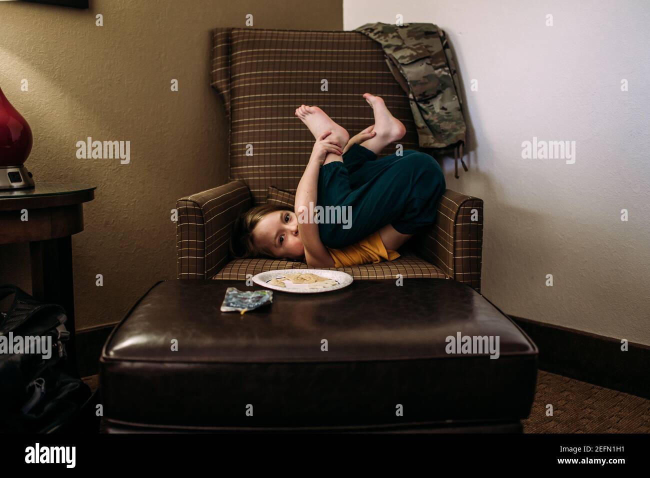 jeune enfant allongé sur une chaise dans une position de goofy Banque D'Images