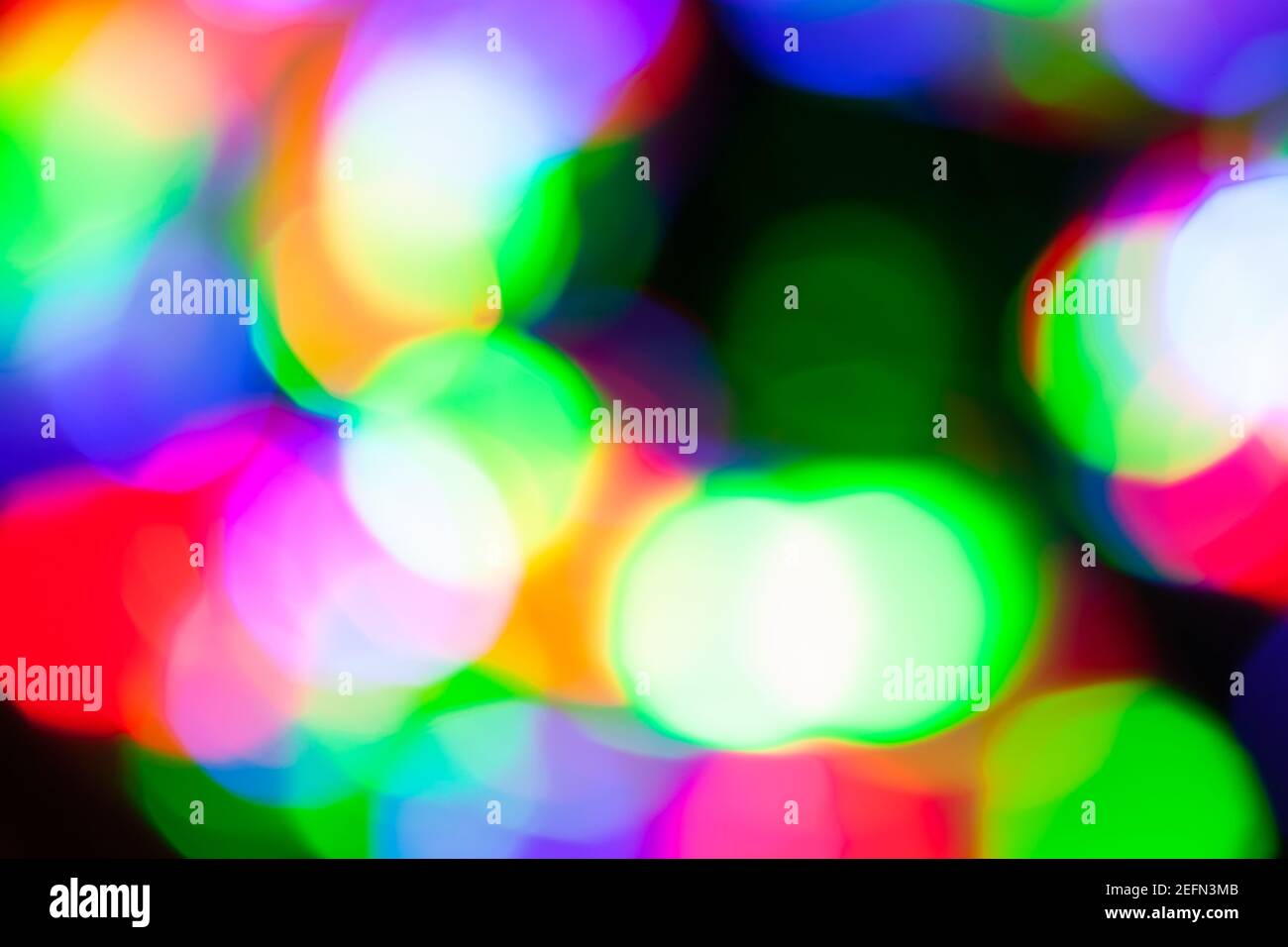 Lumières floues colorées, effet bokeh dans l'obscurité. Texture floue de la photo d'arrière-plan abstraite Banque D'Images