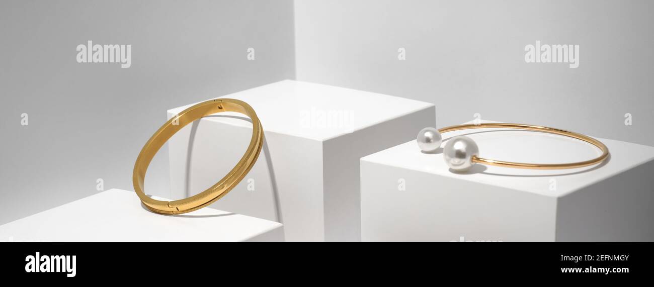 Deux bracelets dorés sur fond géométrique blanc Banque D'Images