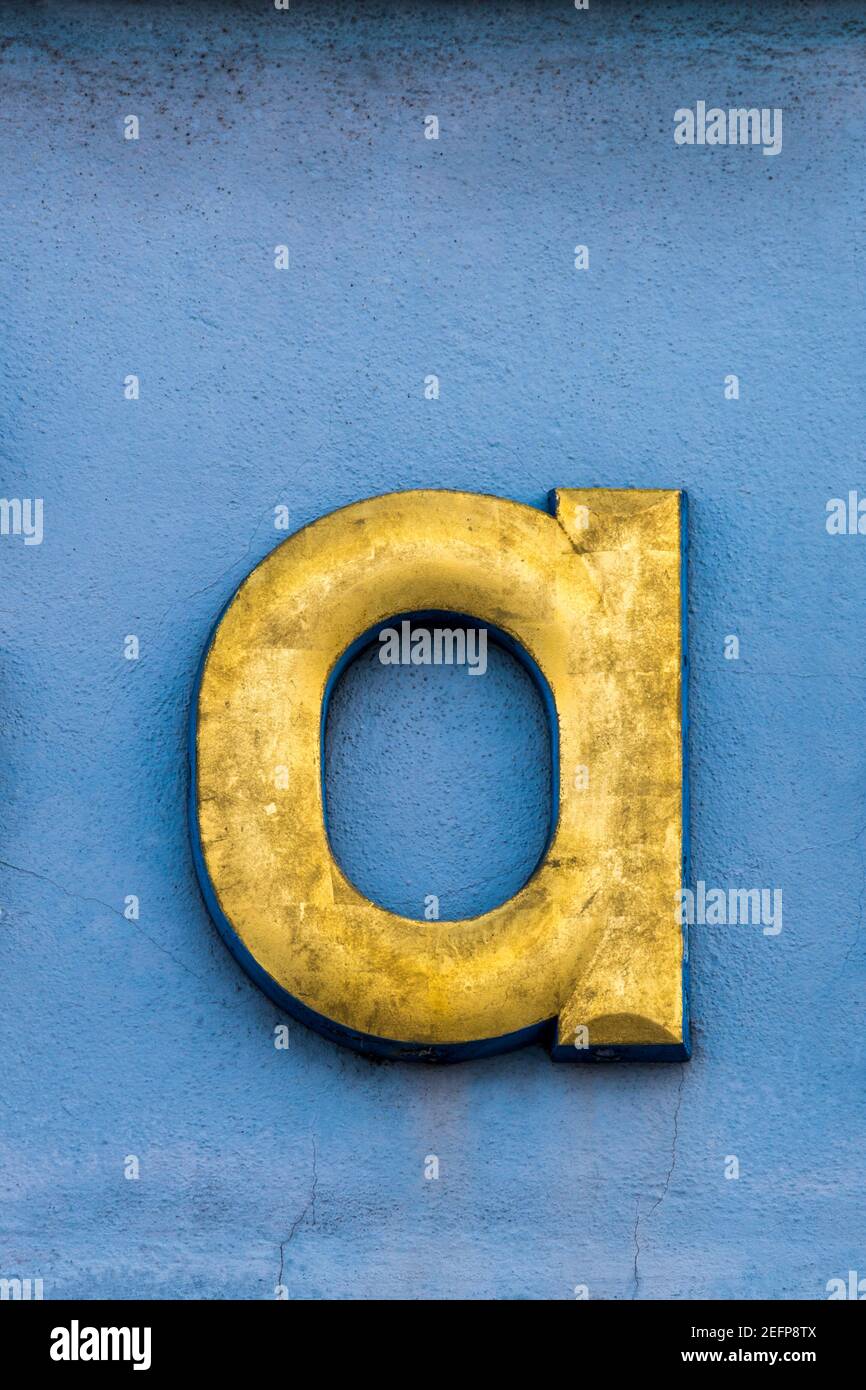 Lettre d'or a devant le mur bleu Banque D'Images