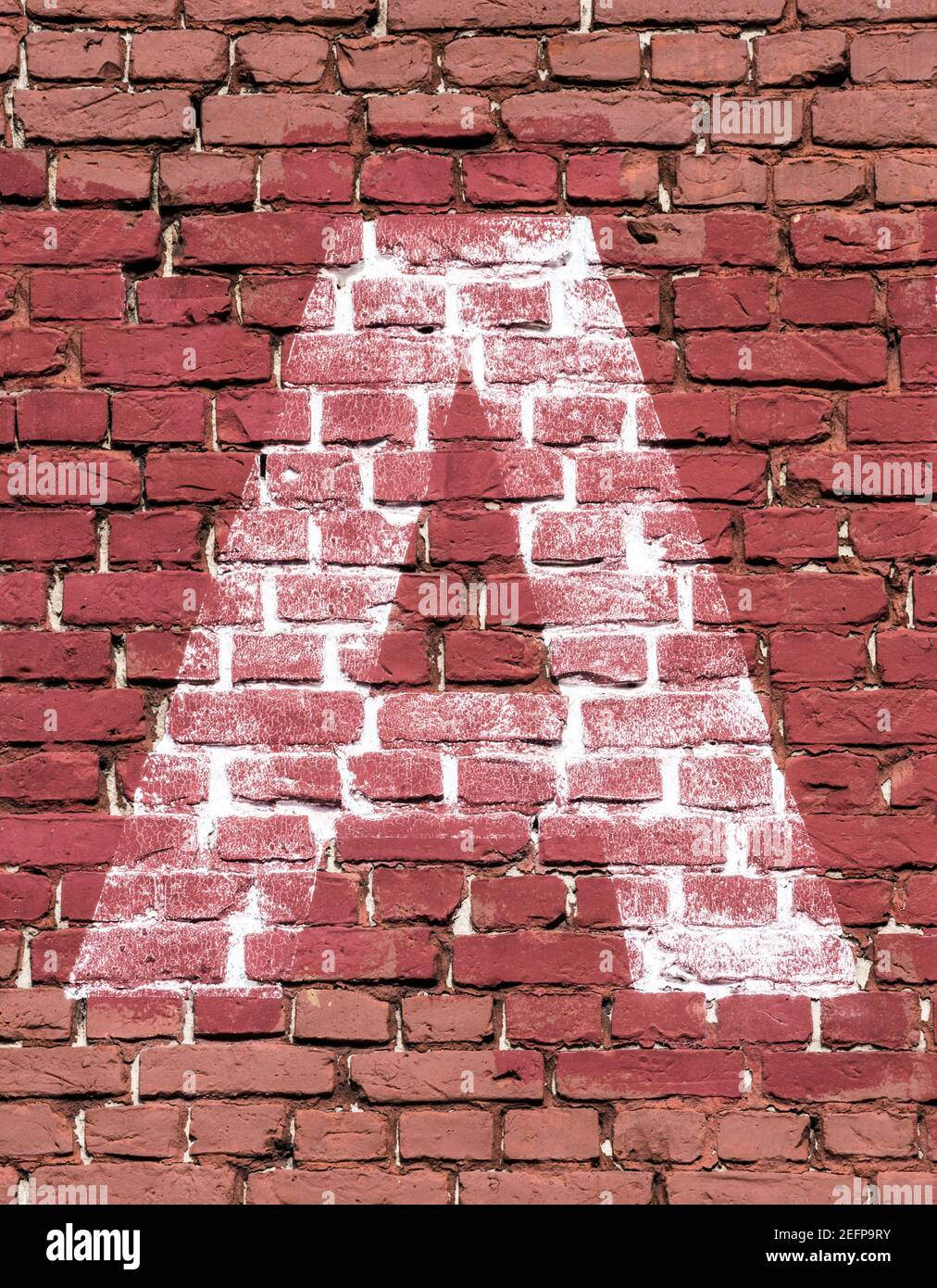La lettre A peint en blanc sur un mur de briques rouges Banque D'Images