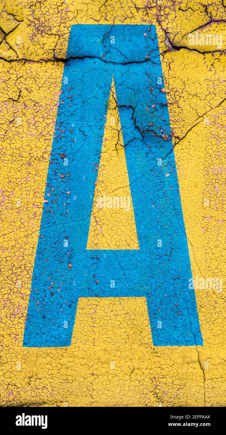 Lettre bleue cyan A peinte sur un mur jaune Banque D'Images