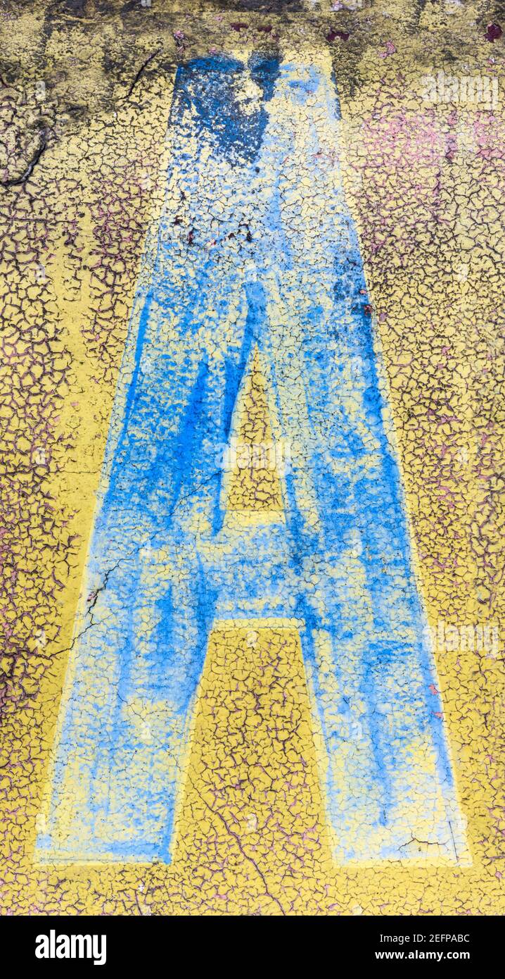 Lettre bleue cyan A peinte sur un mur jaune Banque D'Images