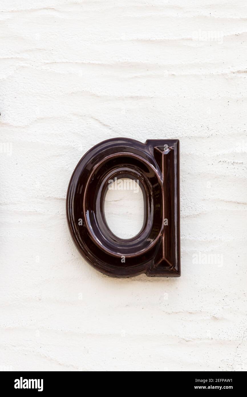 Lettre a émaillée marron foncé sur un mur clair Banque D'Images