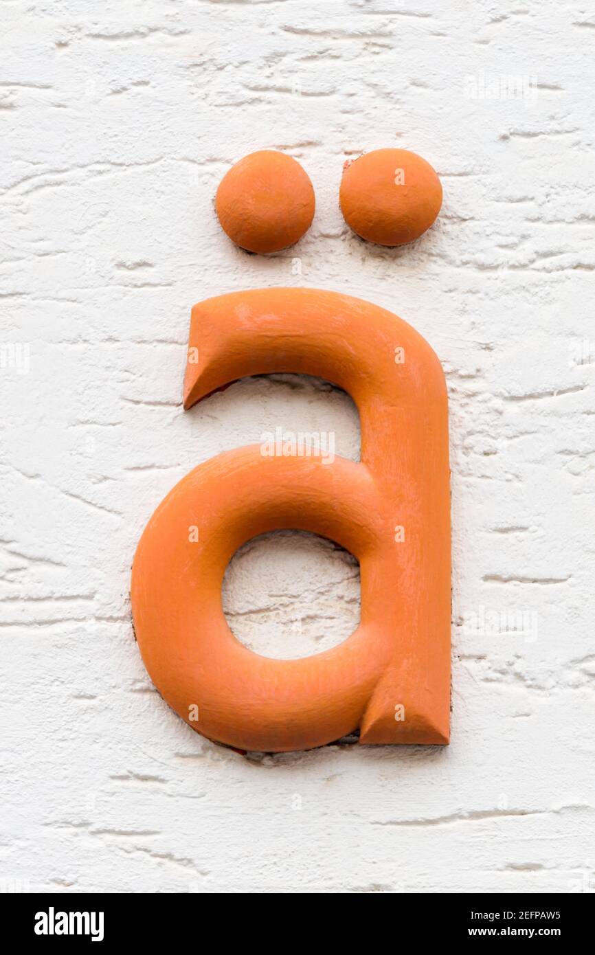 Lettre orange ä, umlaut ae, sur un mur blanc Banque D'Images