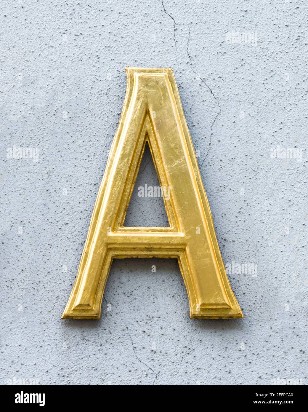 Lettre d'or A sur un mur gris clair Banque D'Images