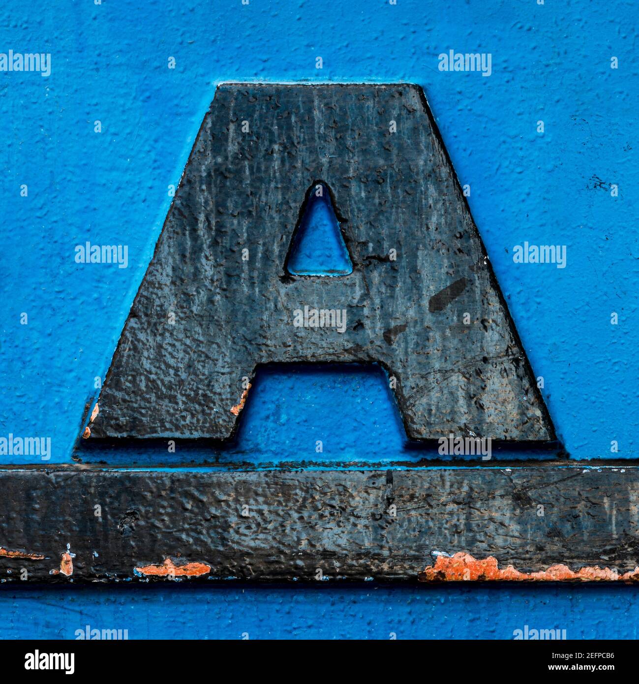 Lettre A en métal noir avec soulignement noir sur fond bleu Banque D'Images