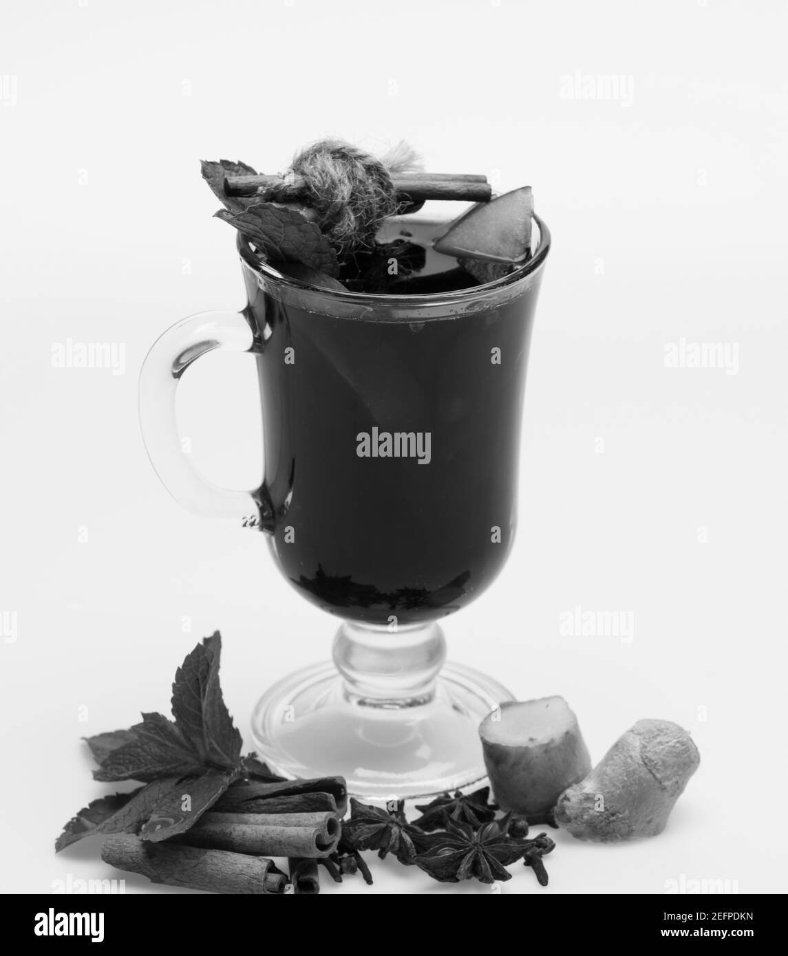 Bâtonnets de cannelle, feuilles de menthe, anis, gingembre, tranches de pomme et carnation au verre. Verre de vin chaud rouge sur fond blanc. Concept de vin domestique. Vin chaud dans des verres et décor. Banque D'Images