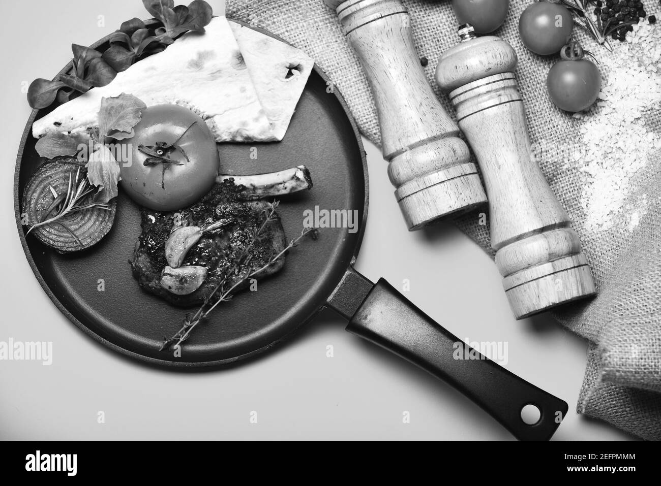 Steak rôti à la tomate, pain plat et oignon grillé. Concept de cuisine traditionnelle. Plat américain près de la boîte aux grains et de la cave à sel. Côtes de porc ou d'agneau avec décor sur poêle, fond jaune. Banque D'Images