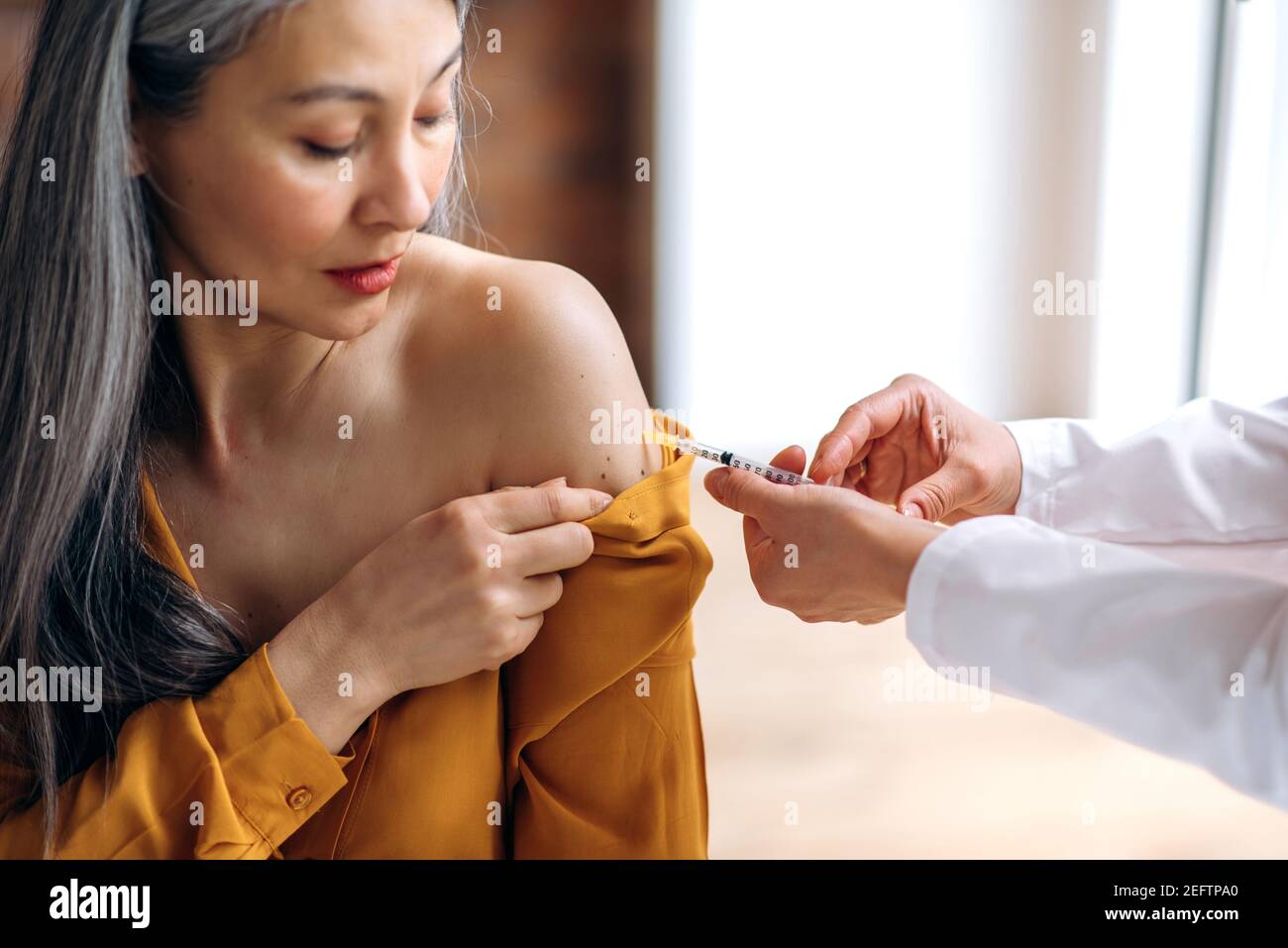Vaccination et prévention de COVID19. Les mains des femmes du médecin ou de l'infirmière administrant l'injection du vaccin à un patient mature à cheveux gris à l'hôpital. Injection de remède de coronavirus dans la femme d'âge moyen Banque D'Images