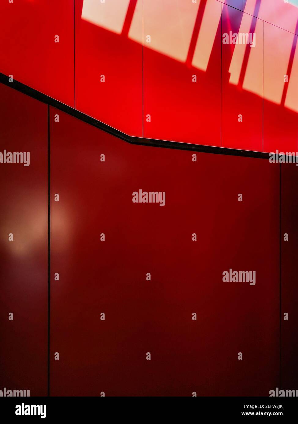 Mur rouge avec bandes noires et rayures ensoleillées Banque D'Images