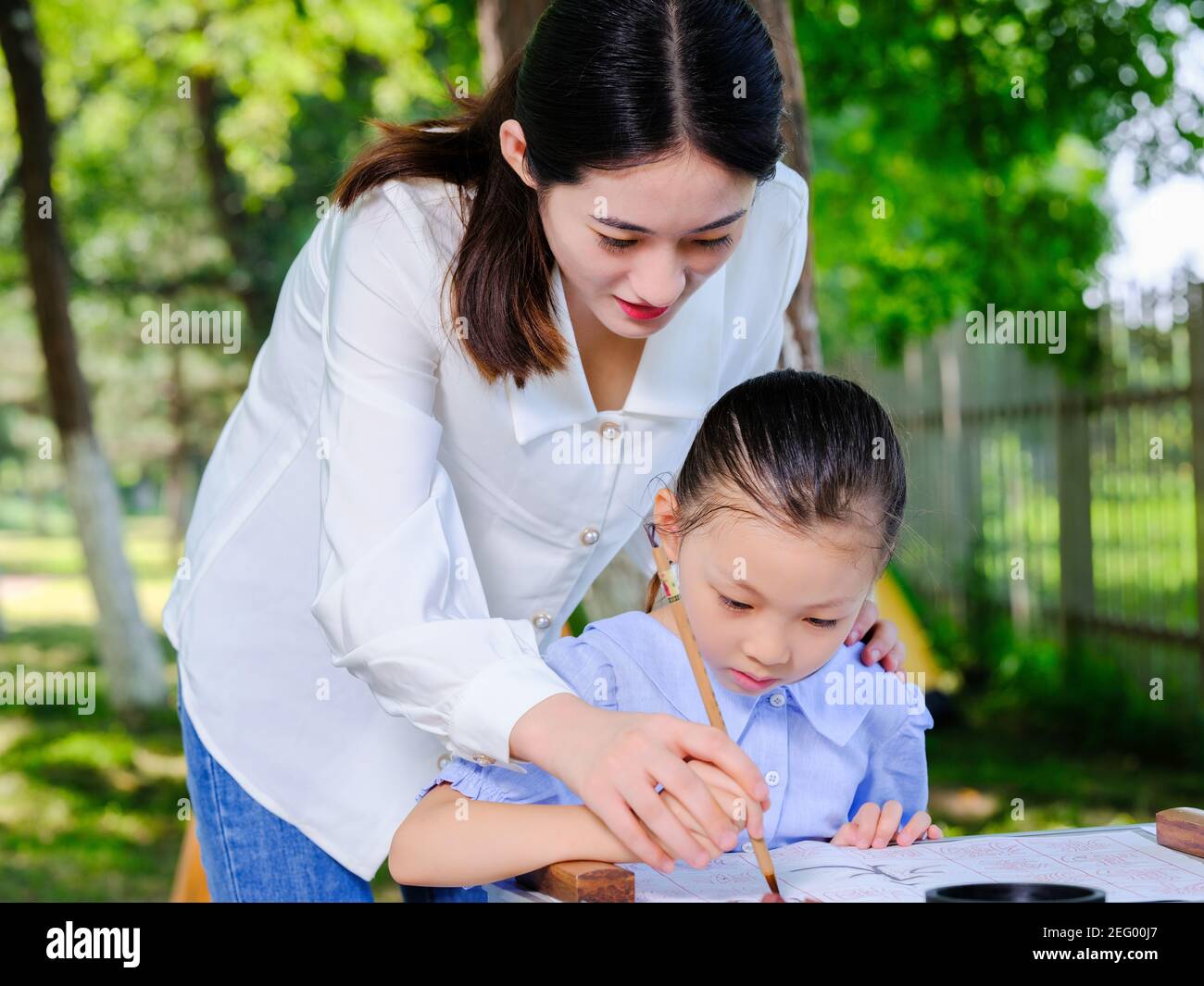 Bonne mère et fille écrire calligraphie à l'extérieur sans regarder le appareil photo Banque D'Images