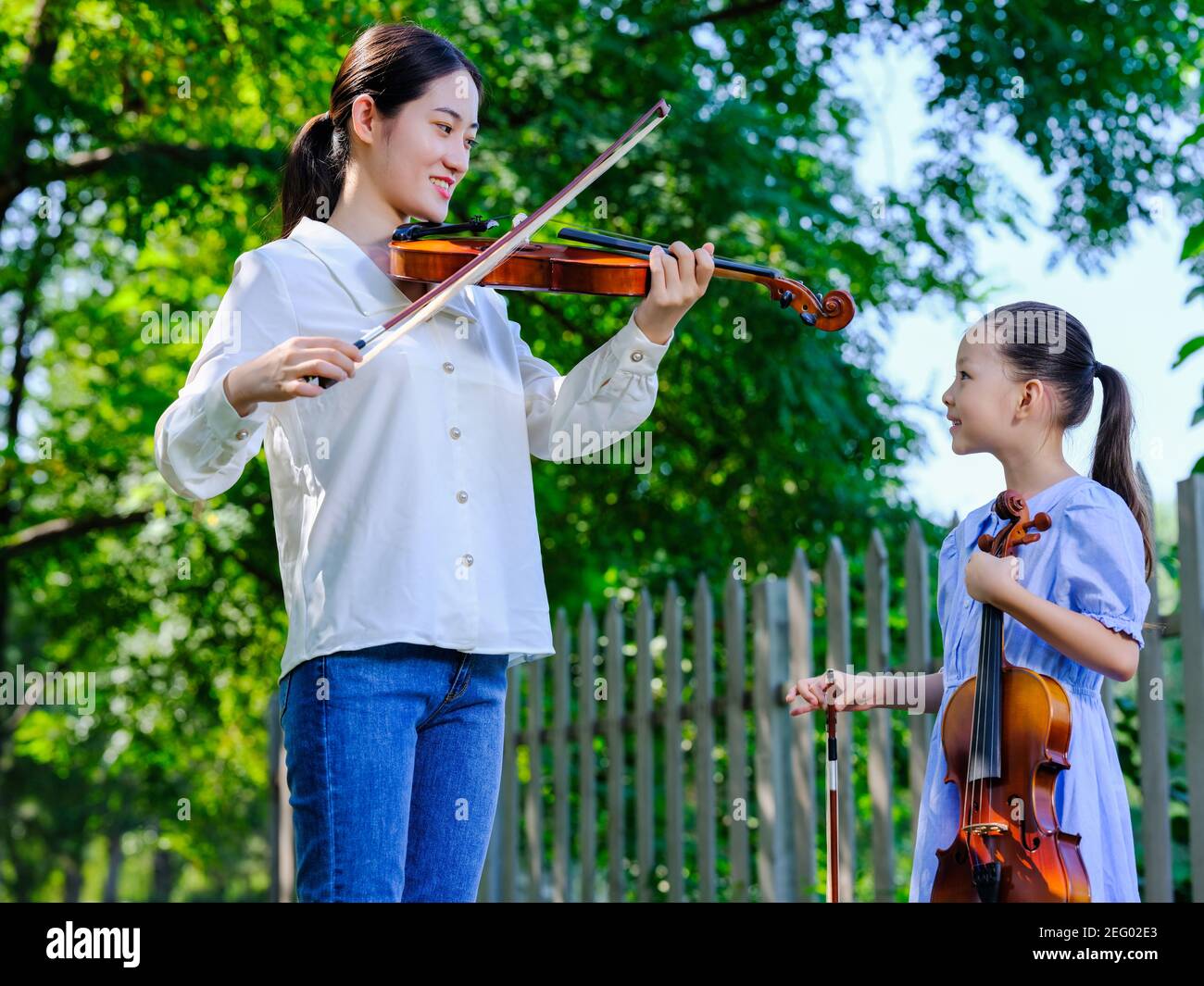 Les jeunes femmes demandent à une petite fille de jouer du violon dans le parc Banque D'Images
