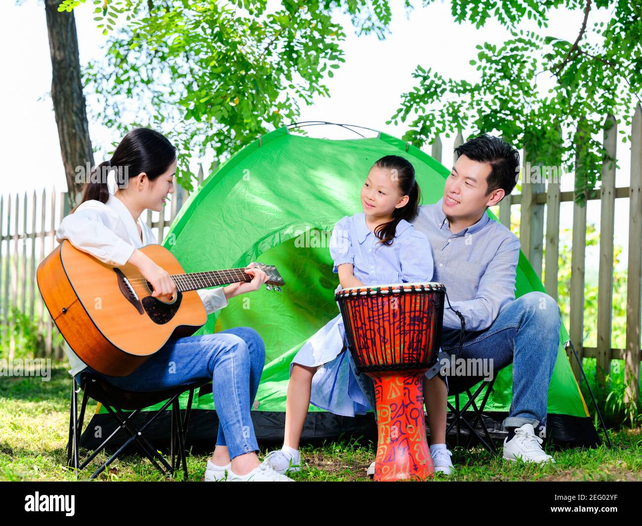 Bonne famille de trois joueurs de guitare dans le parc avec une tente Banque D'Images