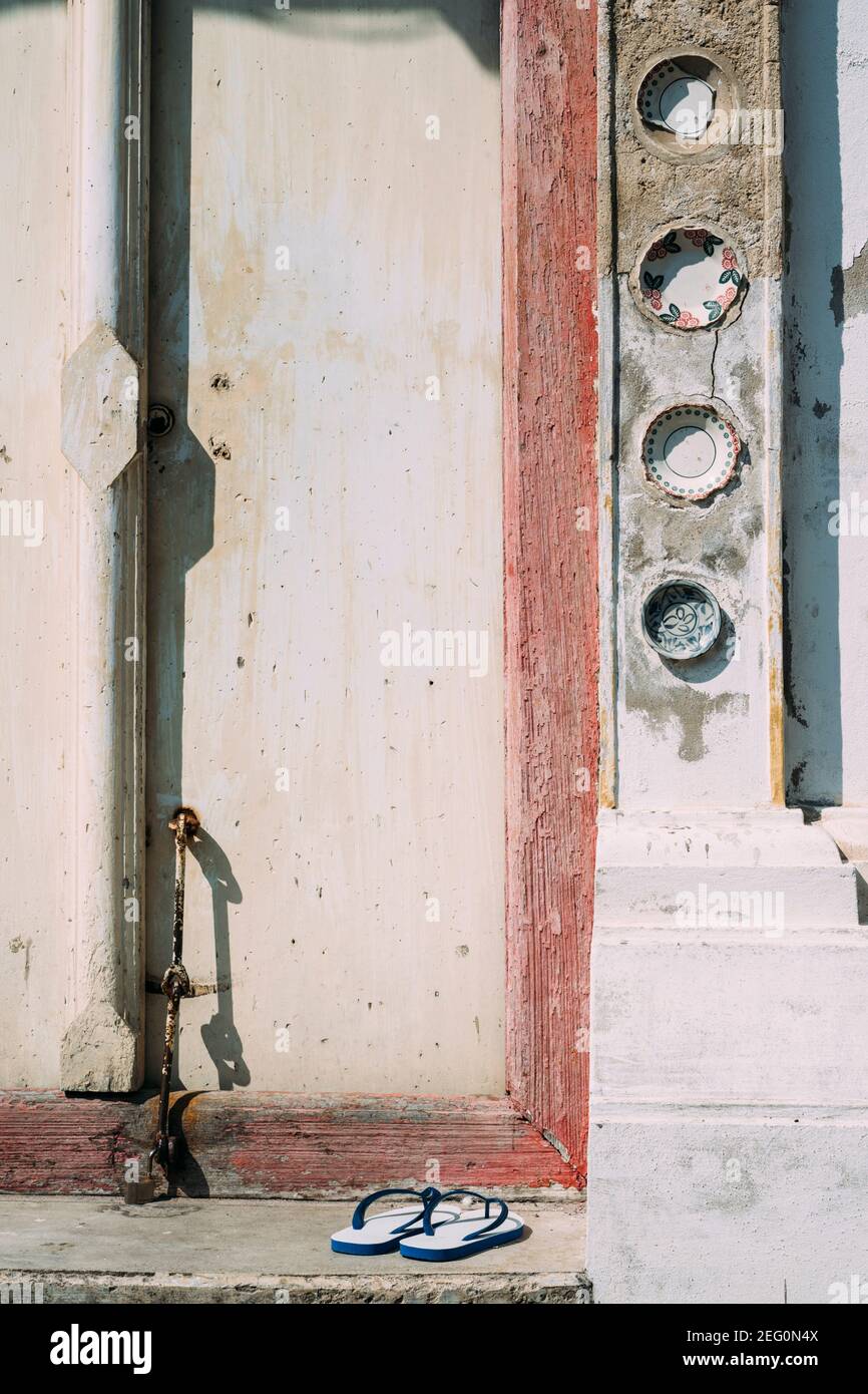 Des chaussures à rabat sont assises devant la porte de l'ancien temple à Pak Nam, en Thaïlande. Banque D'Images