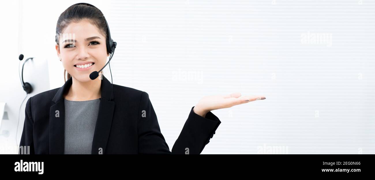 Femme d'affaires asiatique en tant qu'opérateur dans le centre d'appels en train de s'ouvrir mouvement de la main (paume) - bannière panoramique avec espace de copie Banque D'Images