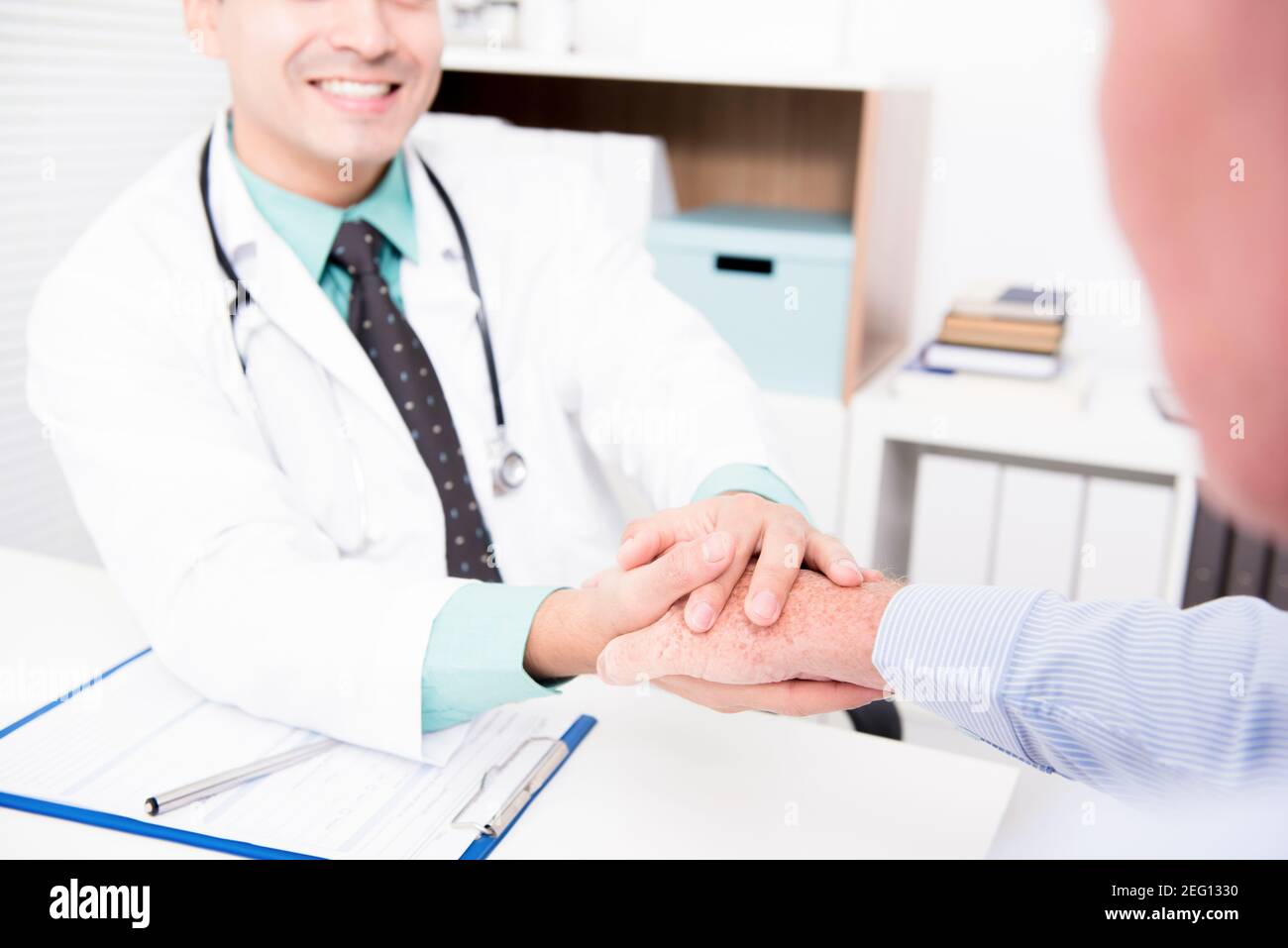 Médecin tenant la main d'un patient mâle âgé avec soin Banque D'Images