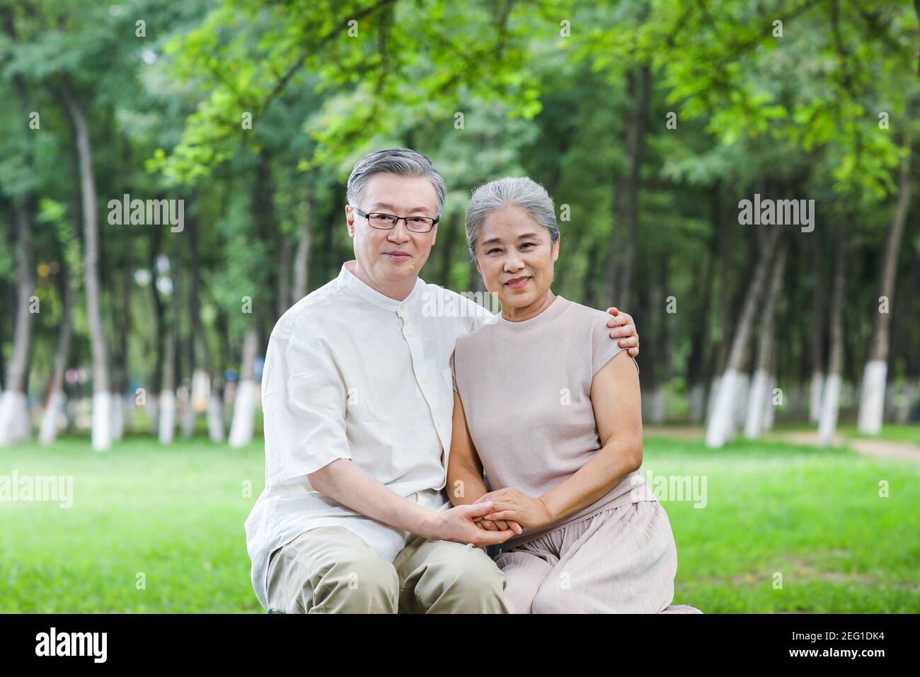 Un vieux couple heureux assis sur les bras de la chaise de stationnement autour épaules Banque D'Images