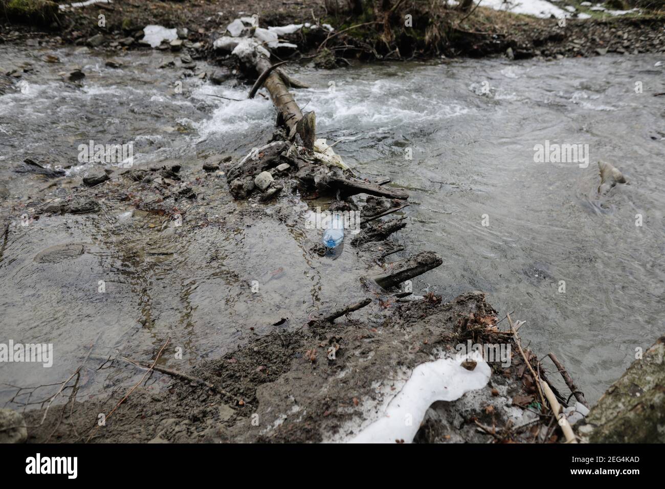 Bouteille en plastique sur un cours d'eau de montagne pendant une journée d'hiver froide et ensoleillée dans les montagnes roumaines des Carpates. Banque D'Images