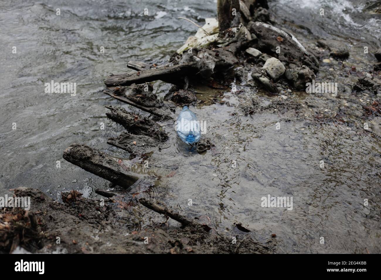 Bouteille en plastique sur un cours d'eau de montagne pendant une journée d'hiver froide et ensoleillée dans les montagnes roumaines des Carpates. Banque D'Images