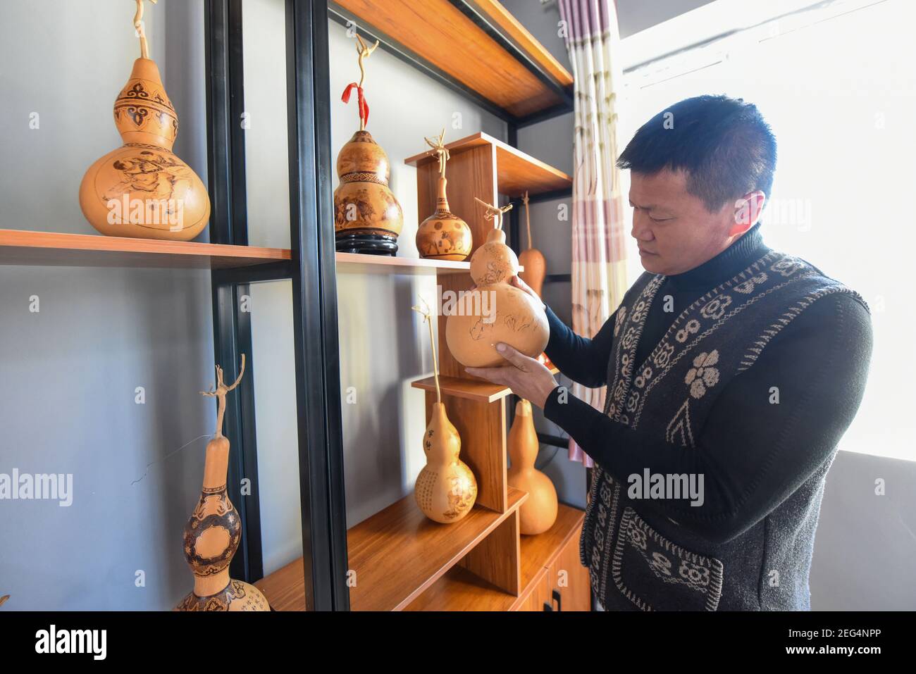 (210218) -- HORGOS, le 18 février 2021 (Xinhua) -- CAO Guangyao évalue des œuvres de calabas pyrographiques dans son studio à Horgos, dans la région autonome de Xinjiang Uygur, dans le nord-ouest de la Chine, le 6 février 2021. CAO Guangyao est un agriculteur de 45 ans à Horgos. Il est également connu par les habitants comme un artiste pour ses œuvres pyrographiques de calabash. En tant que passionné de peinture, Cao s'est intéressé à la création pyrographique il y a 8 ans à partir de séries TV et a commencé sa propre création depuis. En dépit de l'absence de formation professionnelle, Cao a fait des tentatives d'art à maintes reprises avec amour et passion pendant la saison de relâche de l'agriculture Banque D'Images