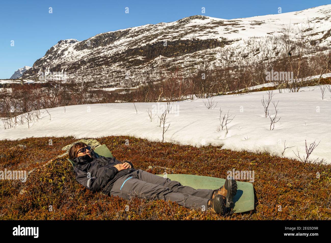 Femme couché au printemps dans la région montagneuse du parc national Stora sjöfallets avec de la neige autour et sur les montagnes, la Laponie suédoise, Swed Banque D'Images