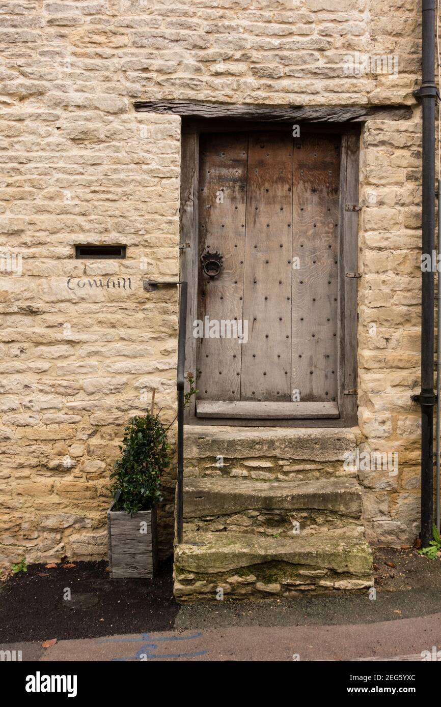 Ancienne porte en bois patientée du cottage en pierre, Minchinhampton, Gloucetershire, Royaume-Uni Banque D'Images