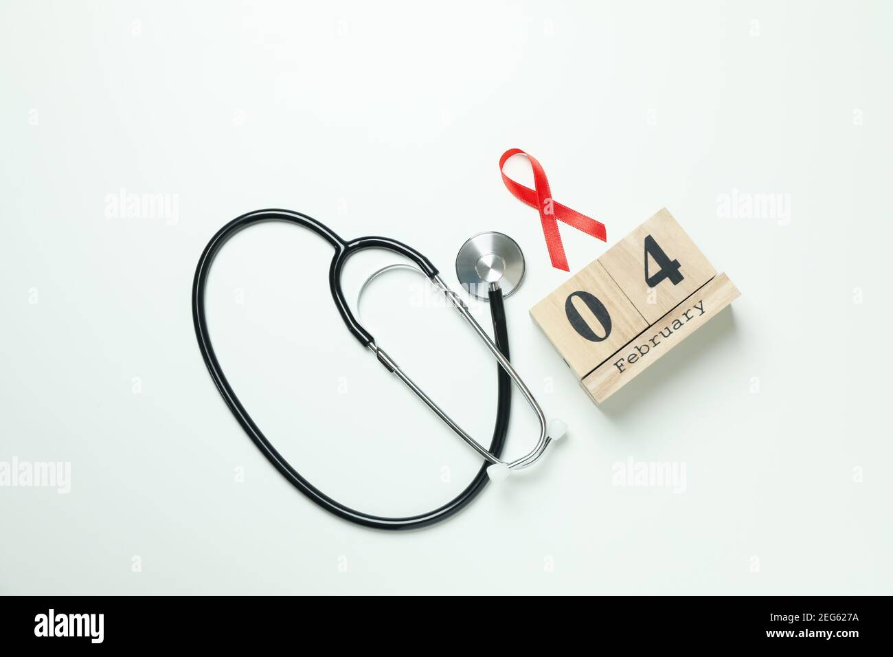 Ruban de sensibilisation rouge, stéthoscope et 4 février sur fond blanc Banque D'Images