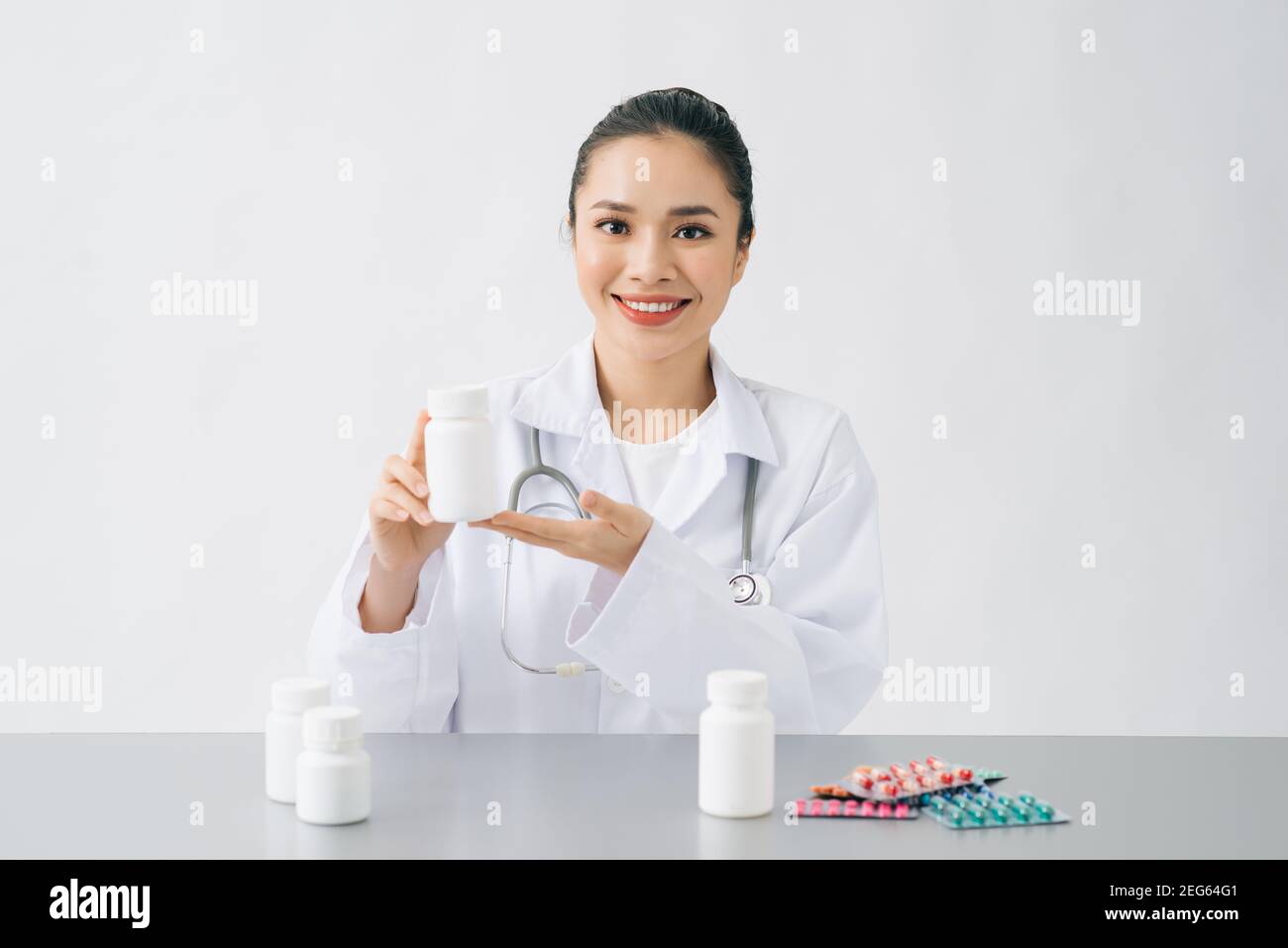 asiatique médecin regardant capsule de vitamine ou de médecine dans une petite bouteille de verre, pour montrer le patient et la médecine de prescription avant d'expliquer comment manger Banque D'Images